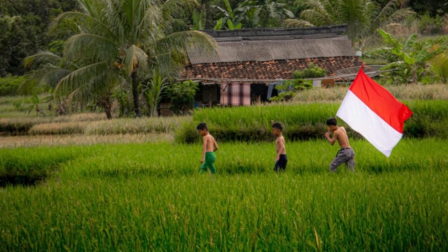 Anak-anak di kampung membawa bendera Merah Putih. [Pexels]
